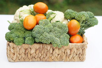 Basket of organic vegetables from garden. Broccoli, cauliflower and tomatoes. Outdoor background. Concept, food ingredient. Healthy eating, source of vitamins, fiber and nutritions. Fresh from garden.