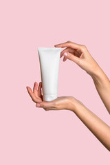 Woman hand showing cream product. Cosmetic product branding mockup. Daily skincare and body care routine. Female hand holding cosmetic product mockup on pink background