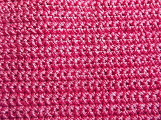 The process of crocheting pink yarn on a purple background