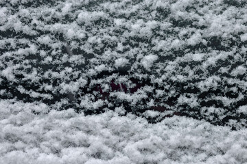 A closeup of an old tractor's front glass covered with snow.