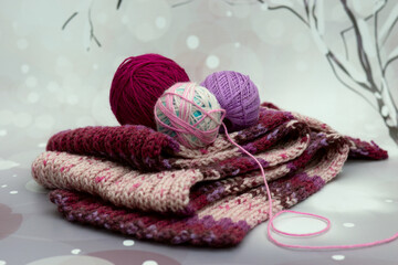 Knitted scarves and yarn on a winter background. Winter poster for interior. Knitted scarves symbolize the cold snowy season.