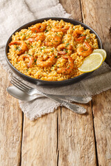 Healthy seafood dish Risotto with shrimp, lemon and fresh herbs closeup on the plate on the wooden table. Vertical
