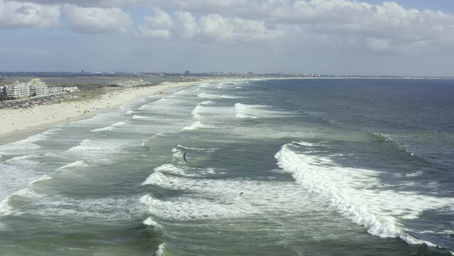 Drone of beach, sea and people kiteboarding in waves for outdoor adventure, travel and holiday or summer vacation. Aerial view of ocean water and surfer surfing in the wind in Cape Town South Africa