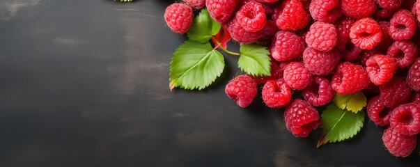 Juicy raspberries with dew drops and green leaves on a slate background. Gourmet food concept with...