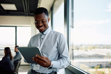 Fototapeta premium Happy black businessman working on digital tablet in office.
