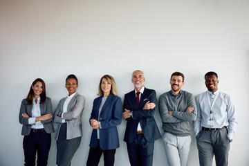 Multiracial group of happy business people against wall looking at camera.