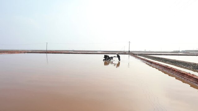 workers drive machinery to work in raw salt crystallization tanks