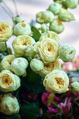 Close-up shot of a bouquet of blooming yellow and white roses with green leaves, blurred background