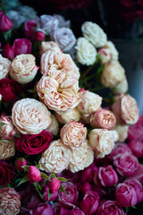 Close-up capture of a bouquet of pink and white roses in full bloom, photographed from above against a blurred, dark background