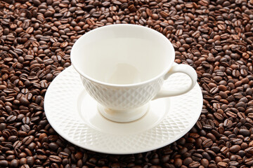 Top view of empty white coffee cup place on surface many roasted coffee beans background.