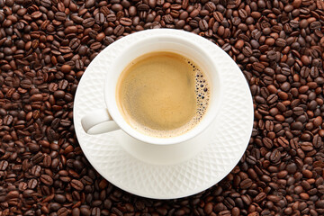 Top view of coffee in white cup place on surface many roasted coffee beans background.