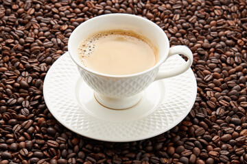 Top view of coffee in white cup place on surface many roasted coffee beans background.