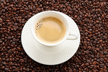 Top view of coffee in white cup place on surface many roasted coffee beans background.