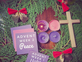 Advent week 2 peace text on paper with the second candle lit and wreath background. Second Advent Sunday concept.