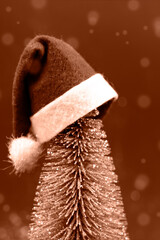 Christmas tree in santa claus hat close-up on a dark blurred background. Vertical image. Peach fuzz...