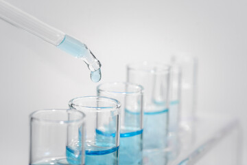 Chemistry laboratory tube glass, science laboratory research and development concept, flask, beaker, and test tubes with dropping blue liquid water sample test, scientific test tubes equipment.