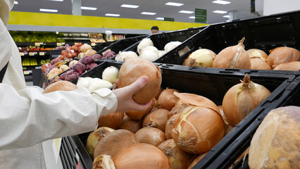 Woman picking fresh onion inside Walmart store