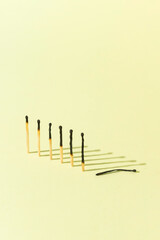 Burned matches on light pastel yellow background. Burned out minimal creative concept. Work week, fatigue, exhaustion at work, stress issues. Copy space.