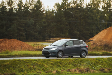 Driving fast on a road surrounded by greenery in a modern hatchback. Side view of modern hatchback...