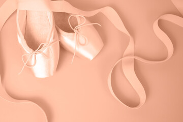 Romantic background. Satin ballet pointe shoes. Peach fuzz is color of year 2024.