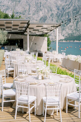 Festive tables on a wooden deck in the garden above the sea against the backdrop of mountains