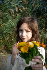 Fototapeta premium Closeup portrait of a little girl holding a bouquet of flowers