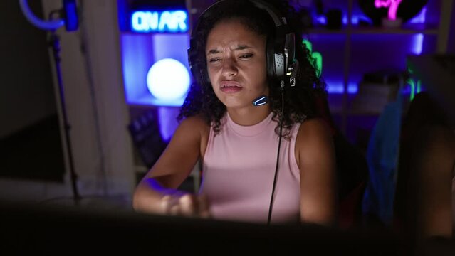 Stressed-out young, beautiful hispanic woman streamer facing stress at gaming, engulfed in digital challenge! overworked, tired in dark gaming room, indoors, streaming online computer game.