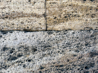 Close-up of a weathered rock wall background with detailed texture and cracks. Suitable for graphic design and background use.