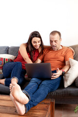 Couple at home sitting on the sofa in amazement while looking at the laptop computer