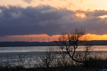 夕焼けの湖畔と風力発電