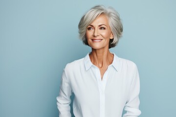 Portrait of smiling senior woman in white shirt on blue background.