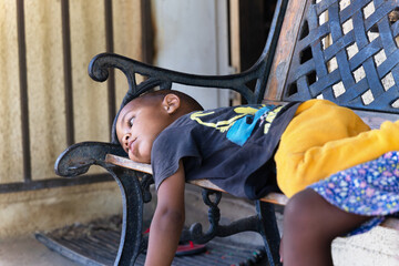 mixed race boy resting on an forged iron bench in front of the house in the favela