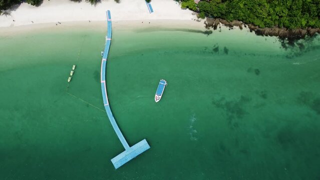 Aerial drone view of boat arriving at tropical island Ko Naka Yai near the coast of Thailand Phuket showing the white beaches and trees and the mountains in the far background on mainland 4k