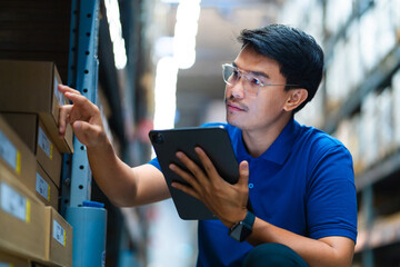 A worker working in a warehouse stands checking equipment on a tablet to check goods in a logistics distribution center. Logistics and export business.
