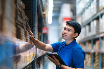 Asian male worker working in warehouse checking product codes between shelves. Logistics business...