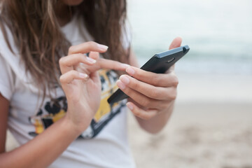 girl with phone on the beach