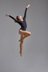 skilled dancer standing on one leg, isolated grey background, hobby, sport interest, woman enjoys her free time, favorite pasttime. full length photo.choreography, being on the height