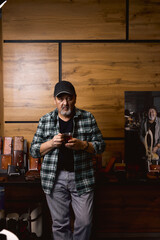 man enjoying coffee, leaning on the table with leather wallets in workshop. portrait. artisan...