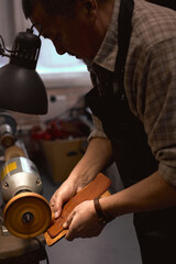 process of sealing and smoothing the rough, raw edges of a leather item. close up side view photo