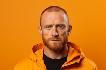 Portrait of a young man with a red beard in a yellow jacket on a yellow background