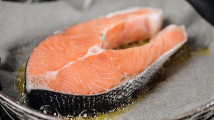 Frying salmon steak on parchment paper with butter