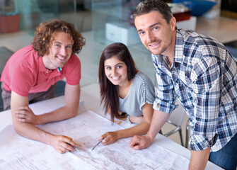 Portrait, happy team and architect on blueprint in office on creative project at startup table. Face, smile and designer group, engineer or professional people drawing paper for construction together