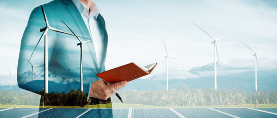 Double exposure graphic of business people working over wind turbine farm and green renewable...