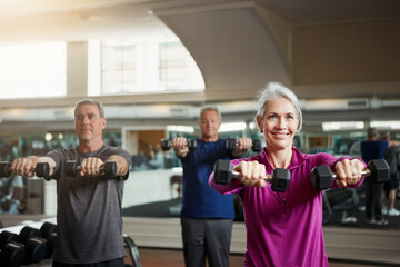 Training, fitness or senior people with dumbbells at gym for club exercise, wellness or cardio, health or strength. Class, workout or elderly friends at sport studio for bodybuilding or weightlifting