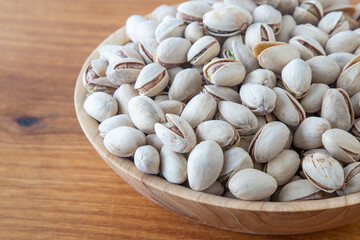 Pistachios in a wooden bowl. Wooden background. Healthy food