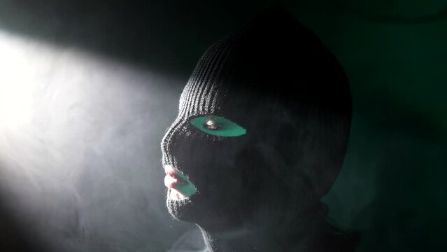 closeup portrait of beautiful woman gangster or terrorist in black balaclava on head, female soldier