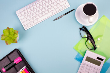 Tablet, calculator, phone, pen and a cup of coffee, lot of things on a blue background. Top view with copy space.