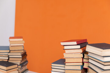 Stacks of educational books in library on orange background
