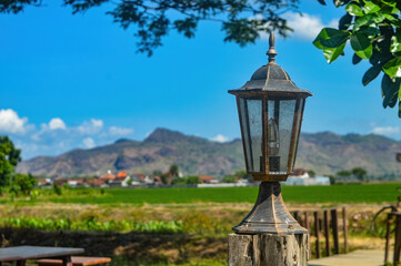 an antique European Nordic style lamp decoration with a backdrop of mountain and rice field views that look blurry and out of focus