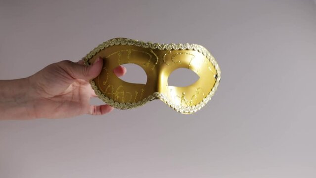 Carnival mask in hand, golden vintage accessory,Venetian masquerade, Italian festivals